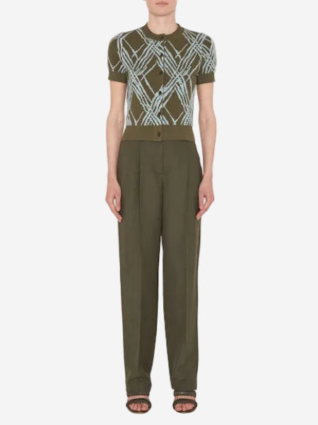 Person wearing a green patterned top and matching pants on a white background