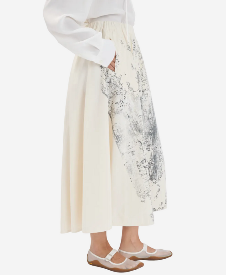 Person wearing a white dress with floral embroidery on a plain background