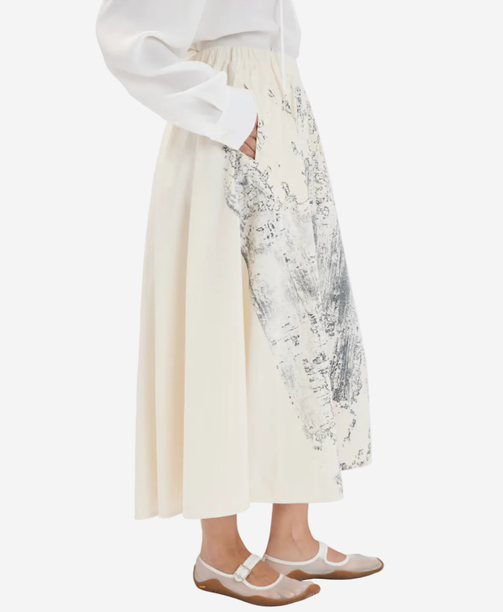 Person wearing a white dress with floral embroidery on a plain background