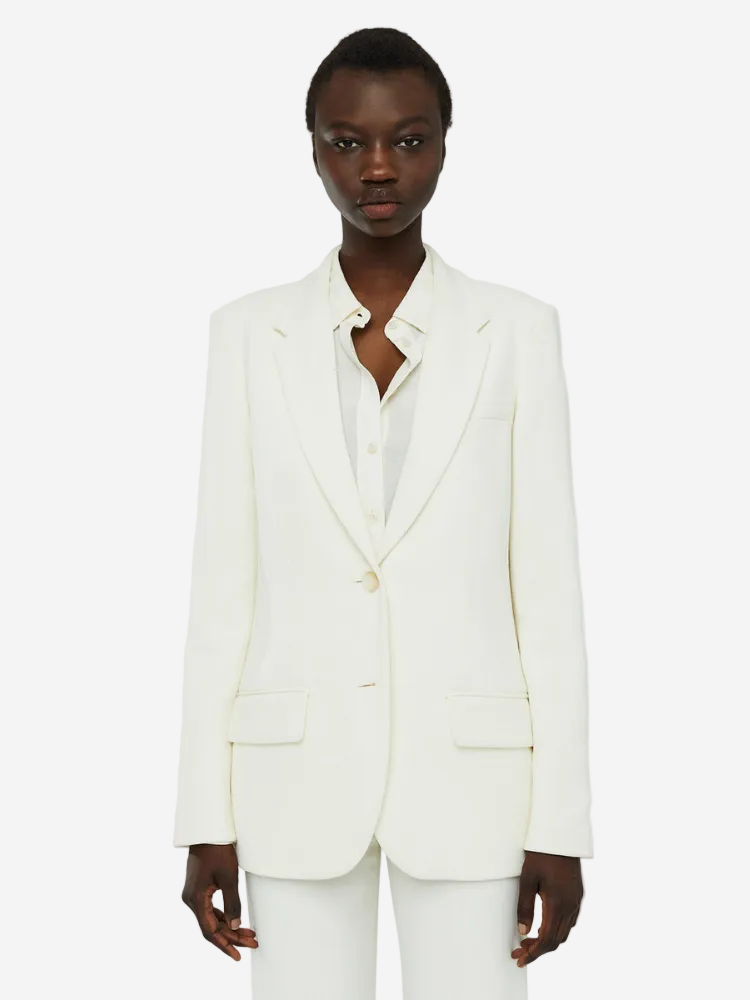 An ivory, single-breasted, regular fit blazer with shoulder padding, flap side pockets, and an inside chest pocket.