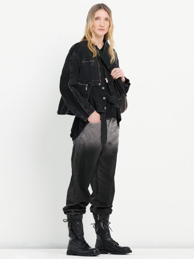 Person wearing a black jacket, black and gray gradient pants, and black boots on a white background