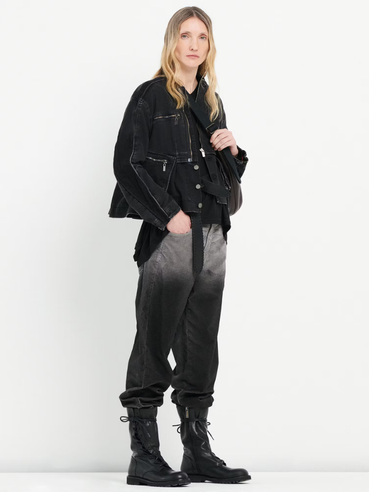 Person wearing a black jacket, black and gray gradient pants, and black boots on a white background