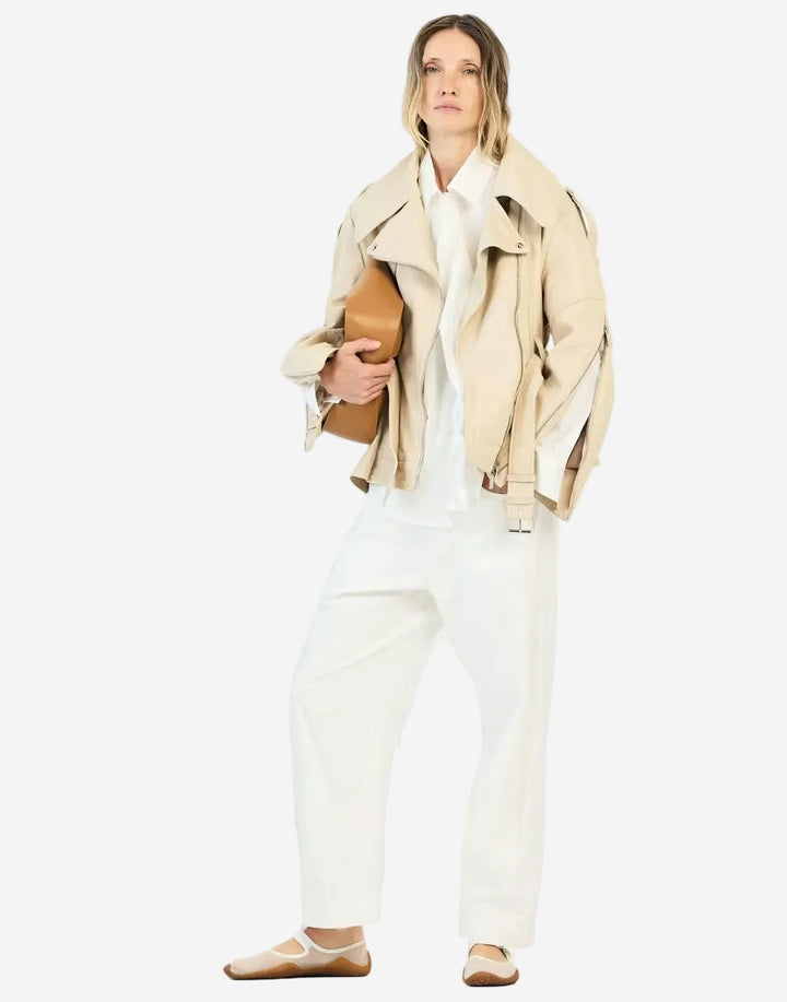 Woman wearing a beige trench coat holding a brown leather bag on a white background