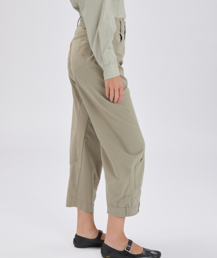 Person wearing beige cargo pants and a light green shirt on a white background