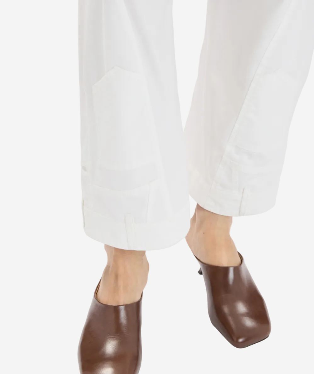 Brown leather shoes worn with white pants on a white background