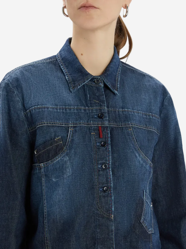 Person wearing a blue denim shirt with a visible brand logo on a white background
