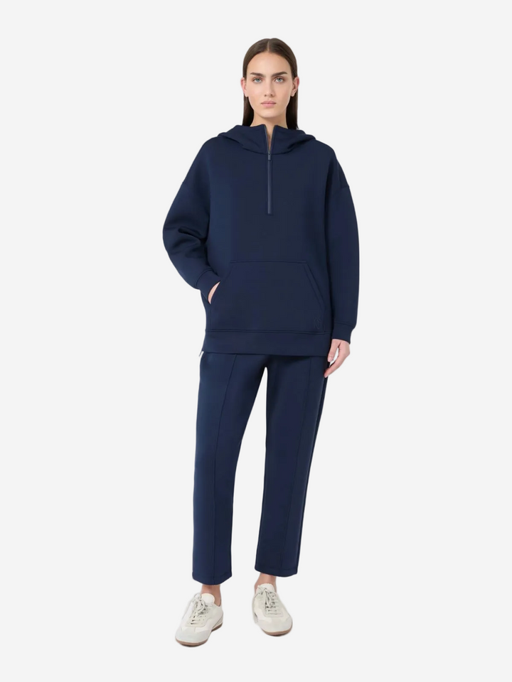 Person wearing a navy blue hoodie and pants on a white background