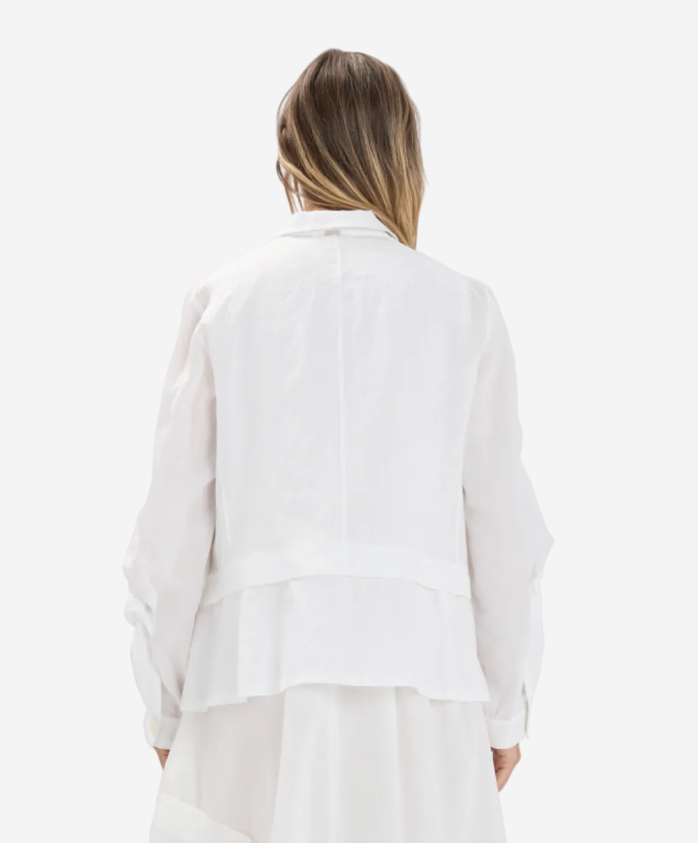 Person wearing a white blouse against a plain background