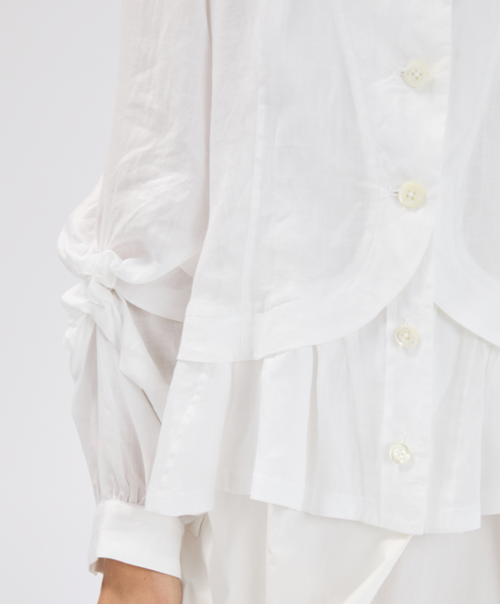 White button-up shirt with ruffled sleeves on a light gray background