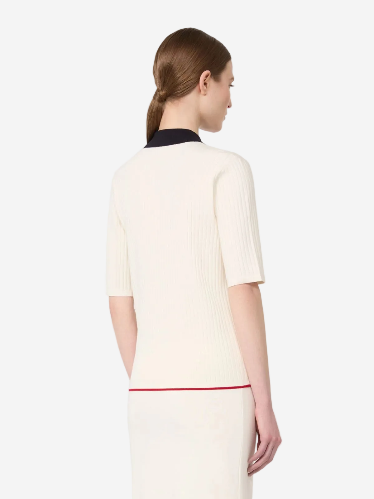 Woman wearing a cream-colored dress with a black collar and red trim on a white background