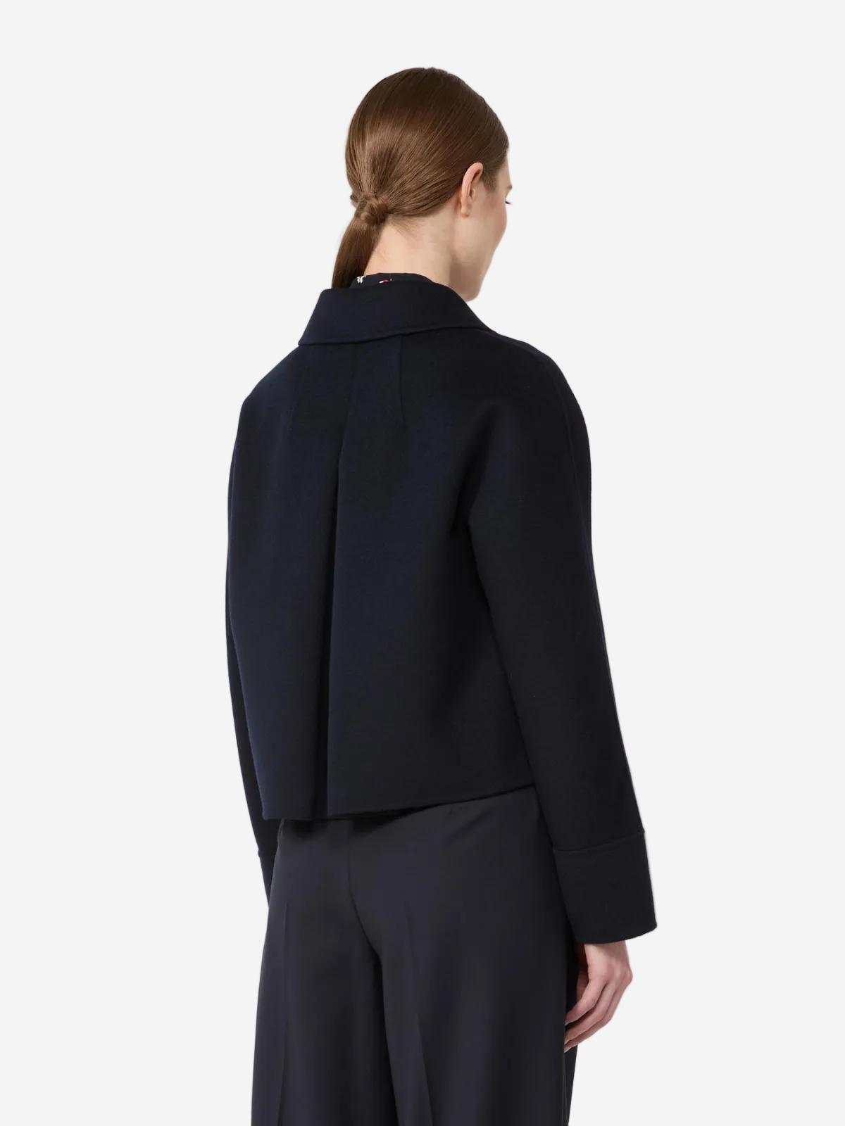 Person wearing a dark blue jacket and pants on a white background