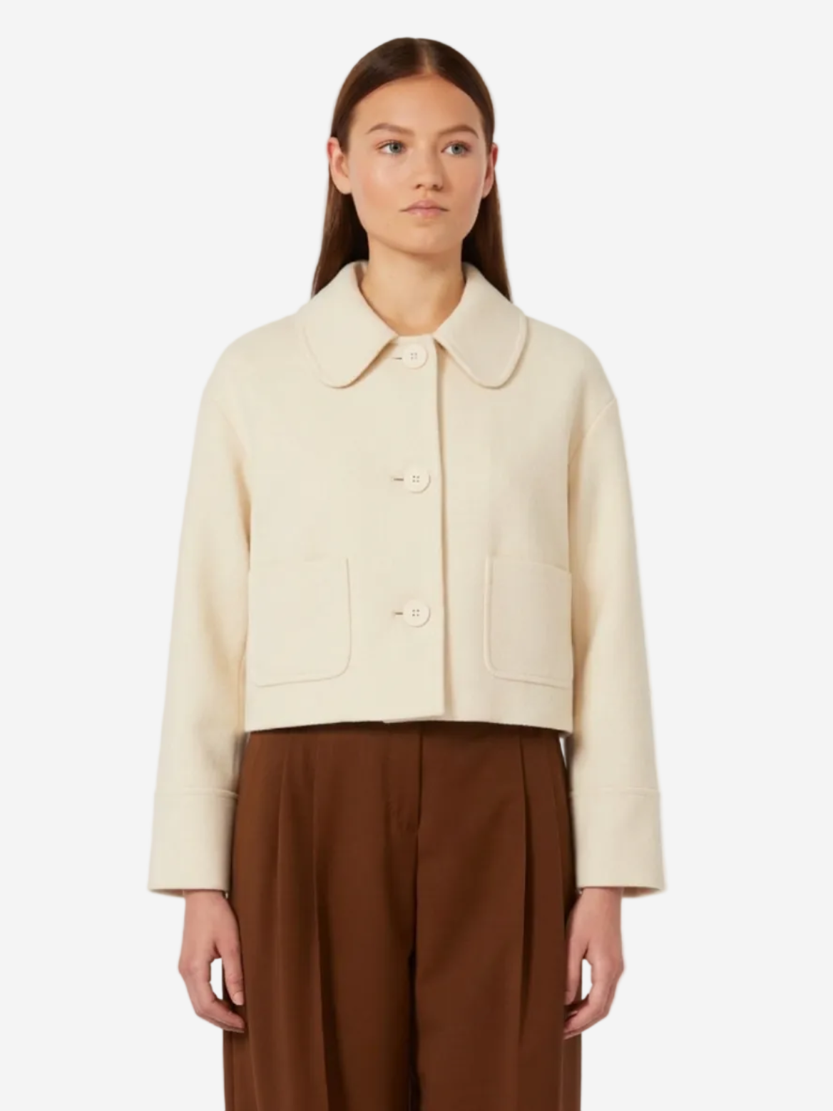 Woman wearing a beige jacket and brown pants on a white background