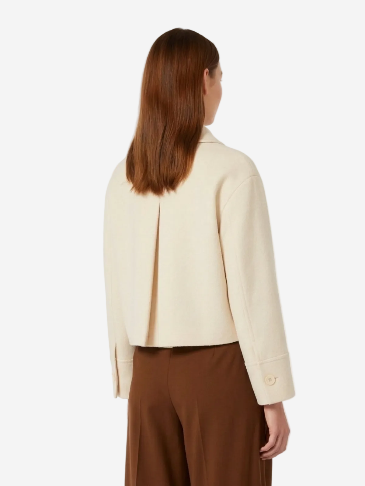 Person wearing a cream blazer and brown pants on a white background