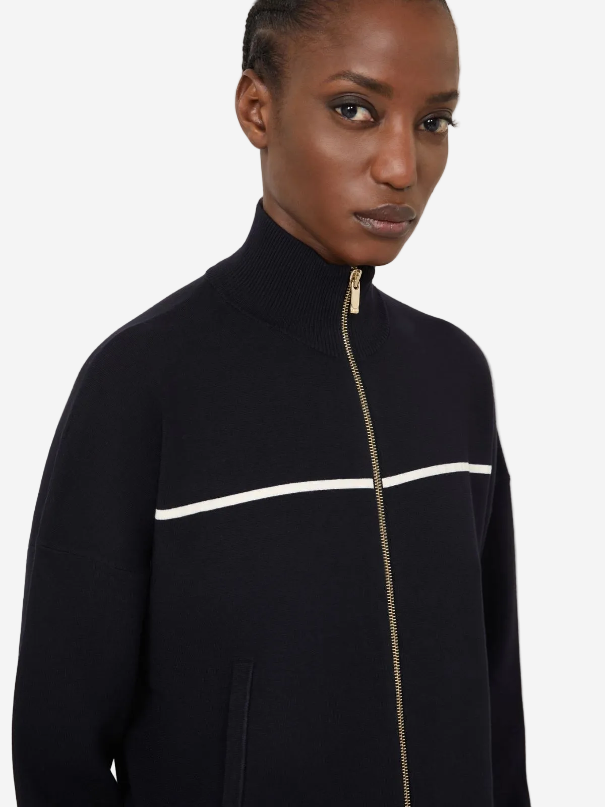 Black jacket with a gold zipper and white stripe worn by a model on a light gray background