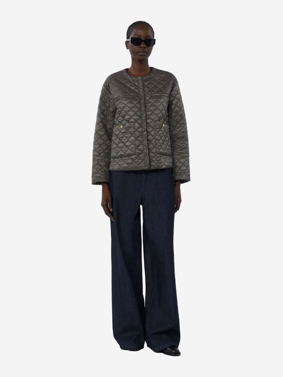 Person wearing a quilted jacket and dark pants on a white background