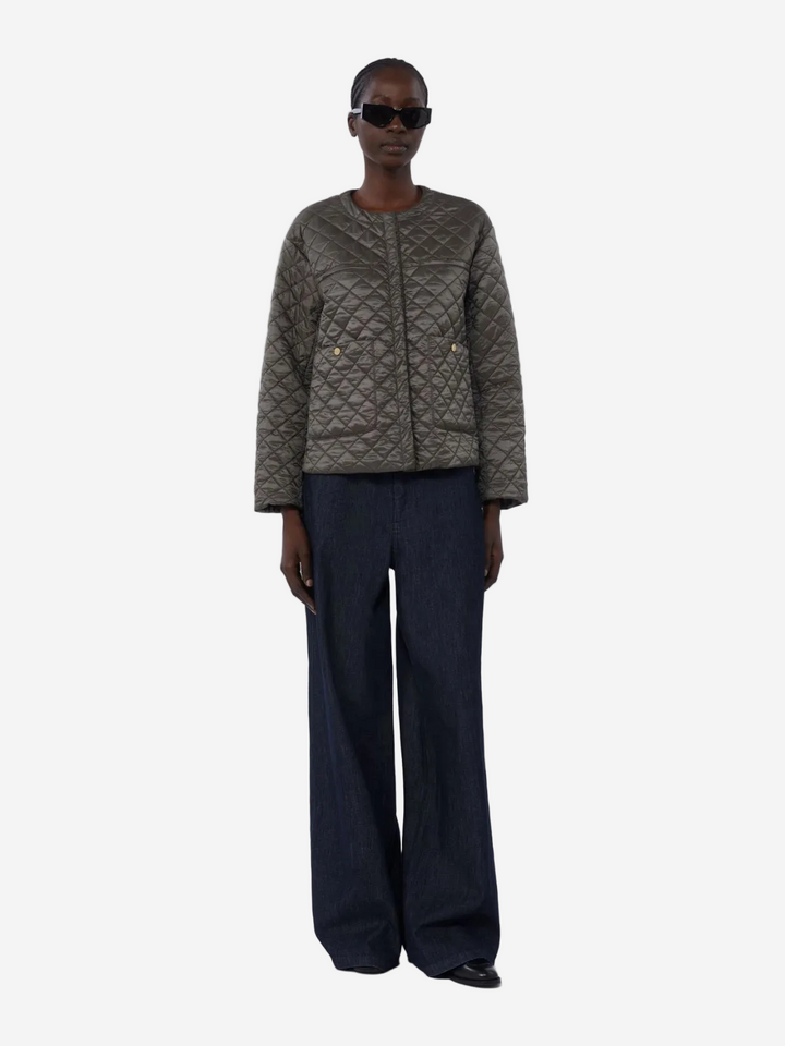 Person wearing a quilted jacket and dark pants on a white background