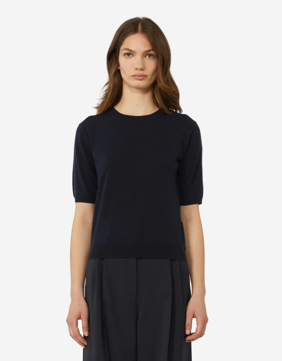 Woman wearing a black top and dark pants on a white background