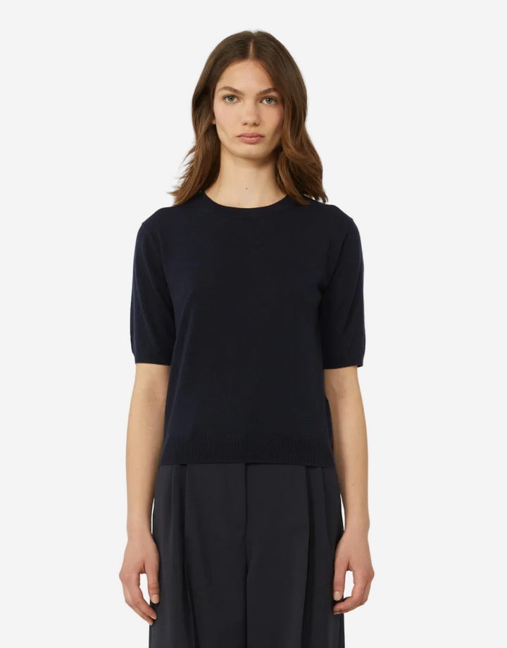 Woman wearing a black top and dark pants on a white background