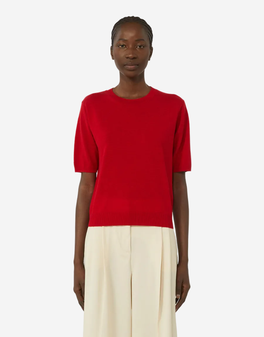 Person wearing a red top and white pants on a white background