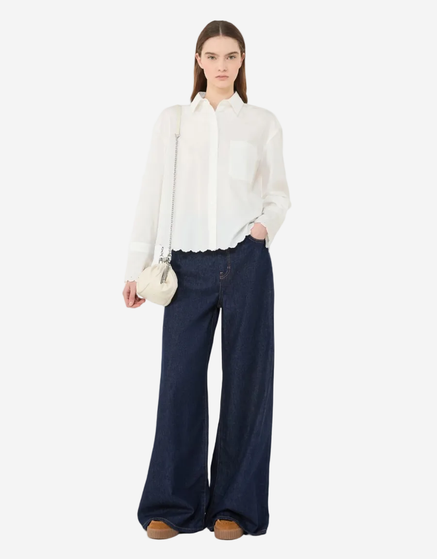 Woman wearing a white blouse and navy pants on a white background