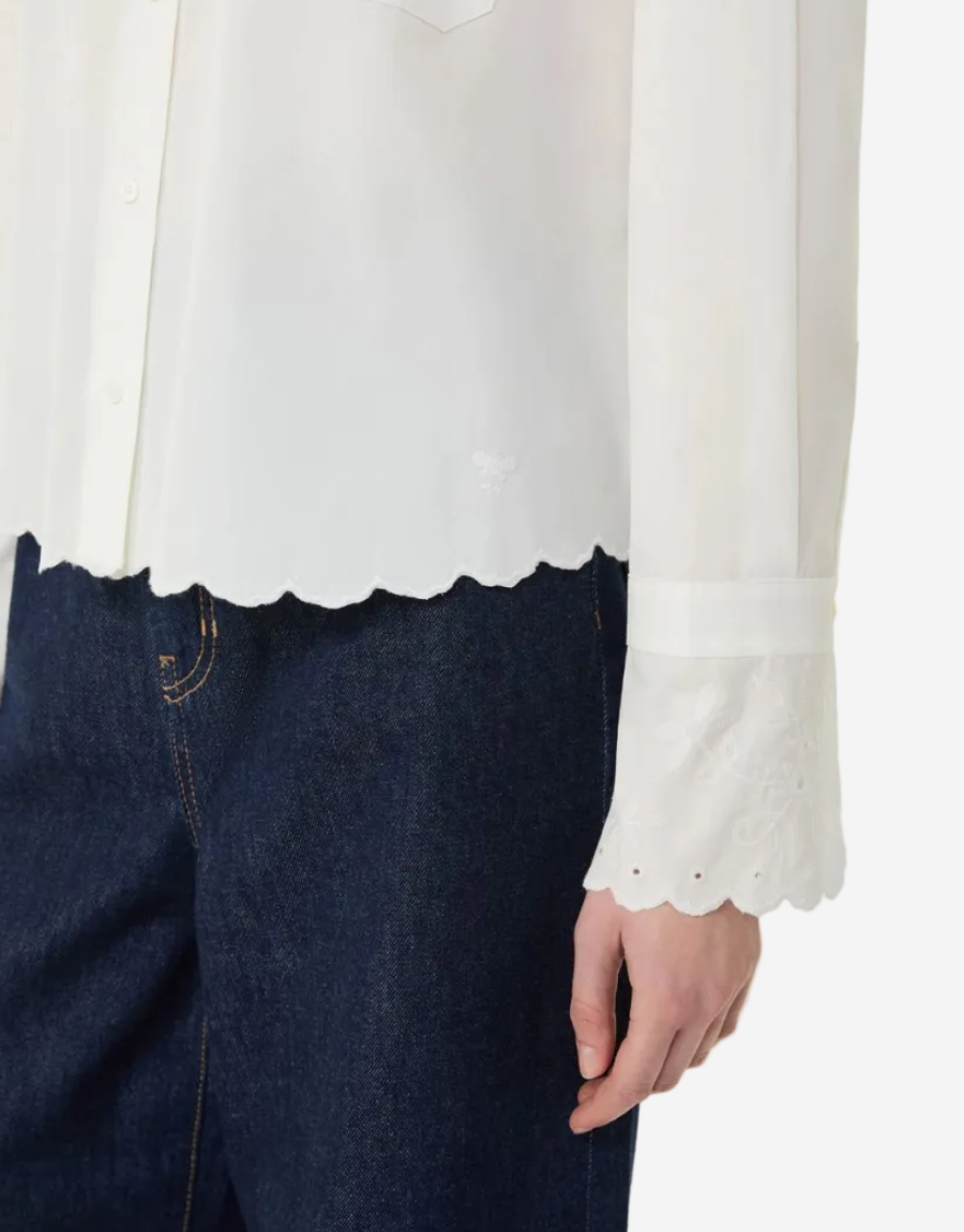 White blouse with scalloped hem and dark blue jeans on a white background