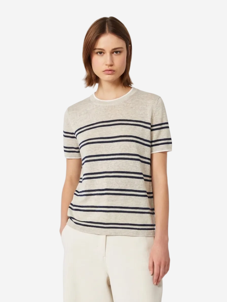 Woman wearing a striped shirt and white pants on a plain background