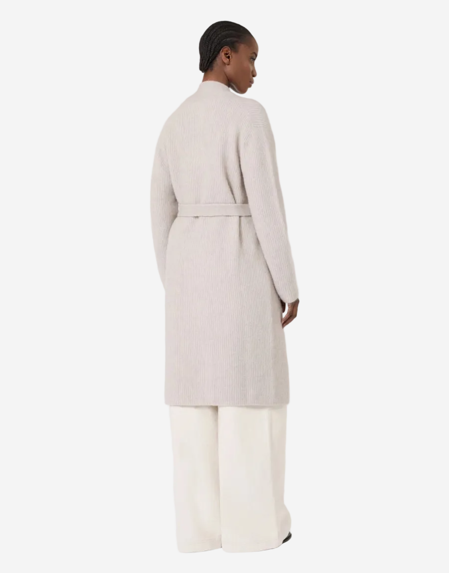 Person wearing a light gray coat and white pants on a white background