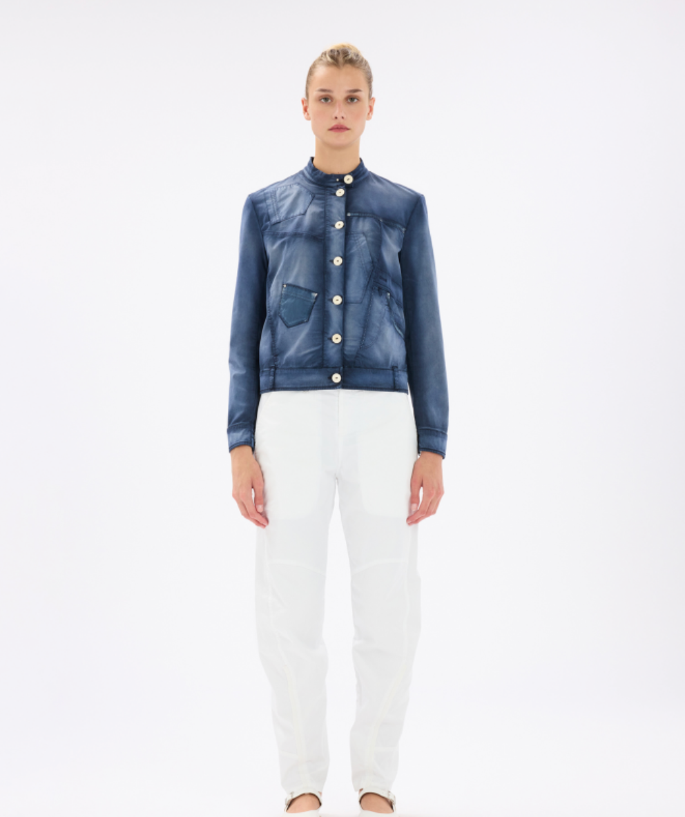 Woman wearing a blue denim jacket and white pants on a white background