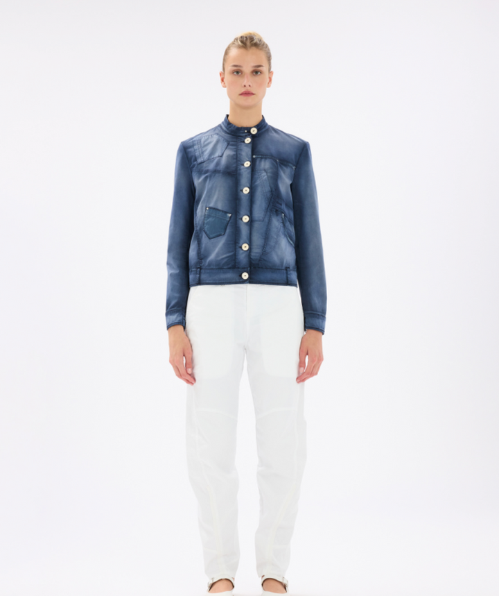 Woman wearing a blue denim jacket and white pants on a white background