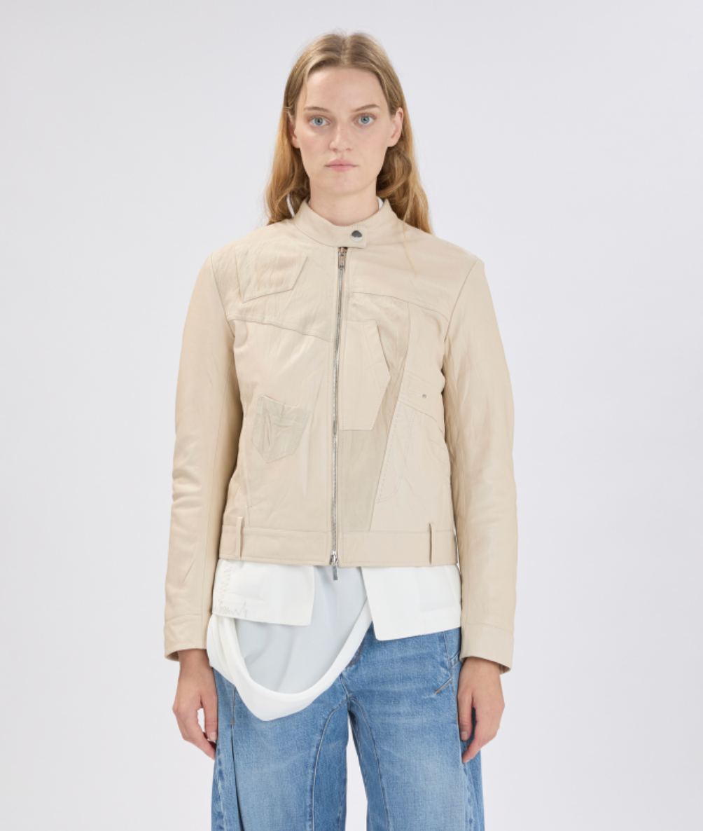 Woman wearing a beige jacket, white shirt, and blue jeans on a white background