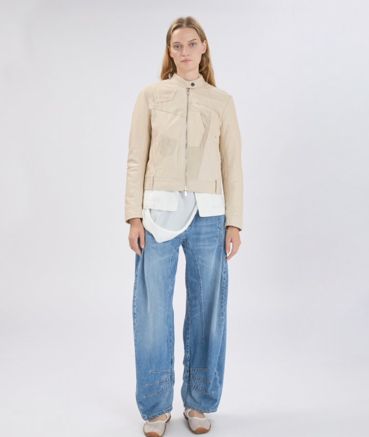Woman wearing a beige jacket and blue jeans on a white background