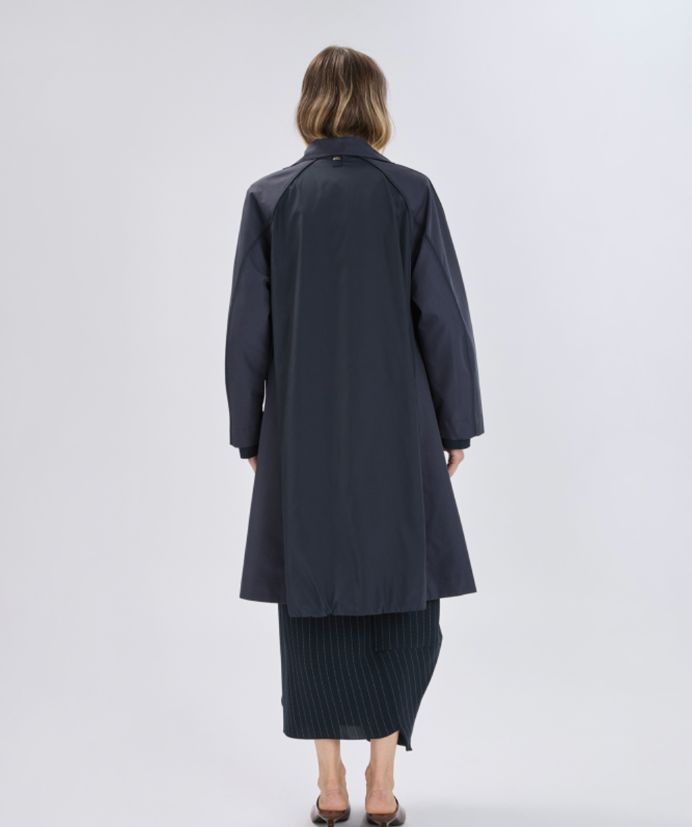 Person wearing a long dark coat on a white background