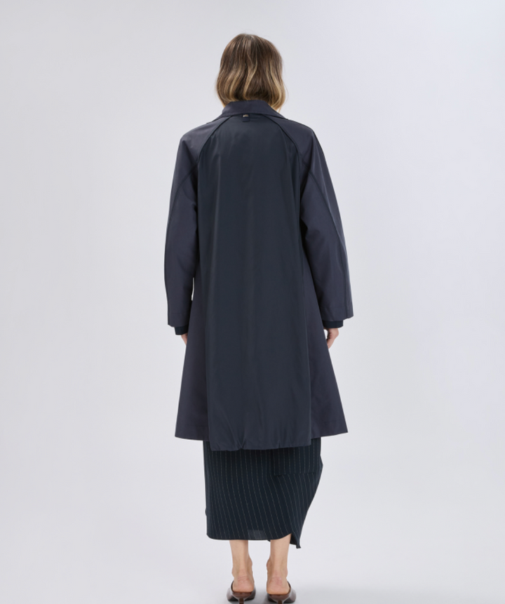 Person wearing a long dark coat on a white background