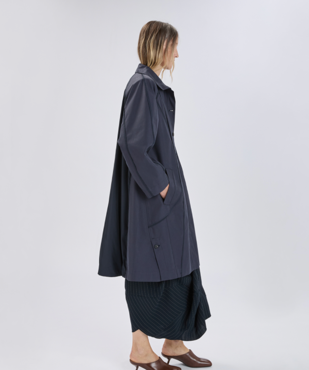 Person wearing a long dark coat on a white background