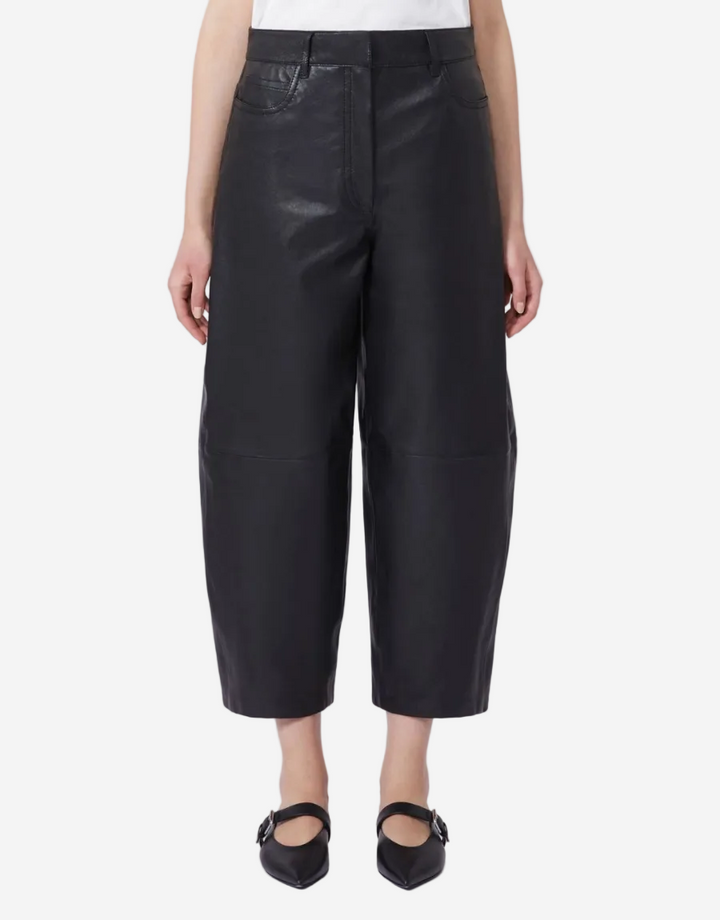 Person wearing black leather pants on a white background