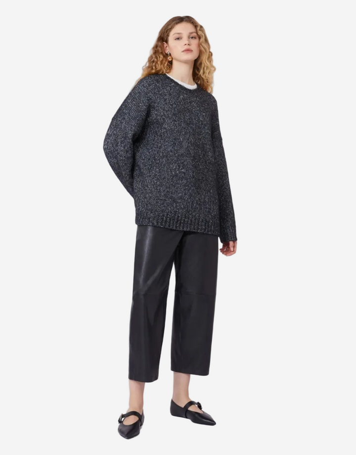 Woman wearing a dark gray sweater and black pants on a white background