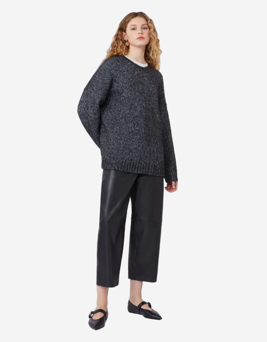 Woman wearing a dark gray sweater and black pants on a white background
