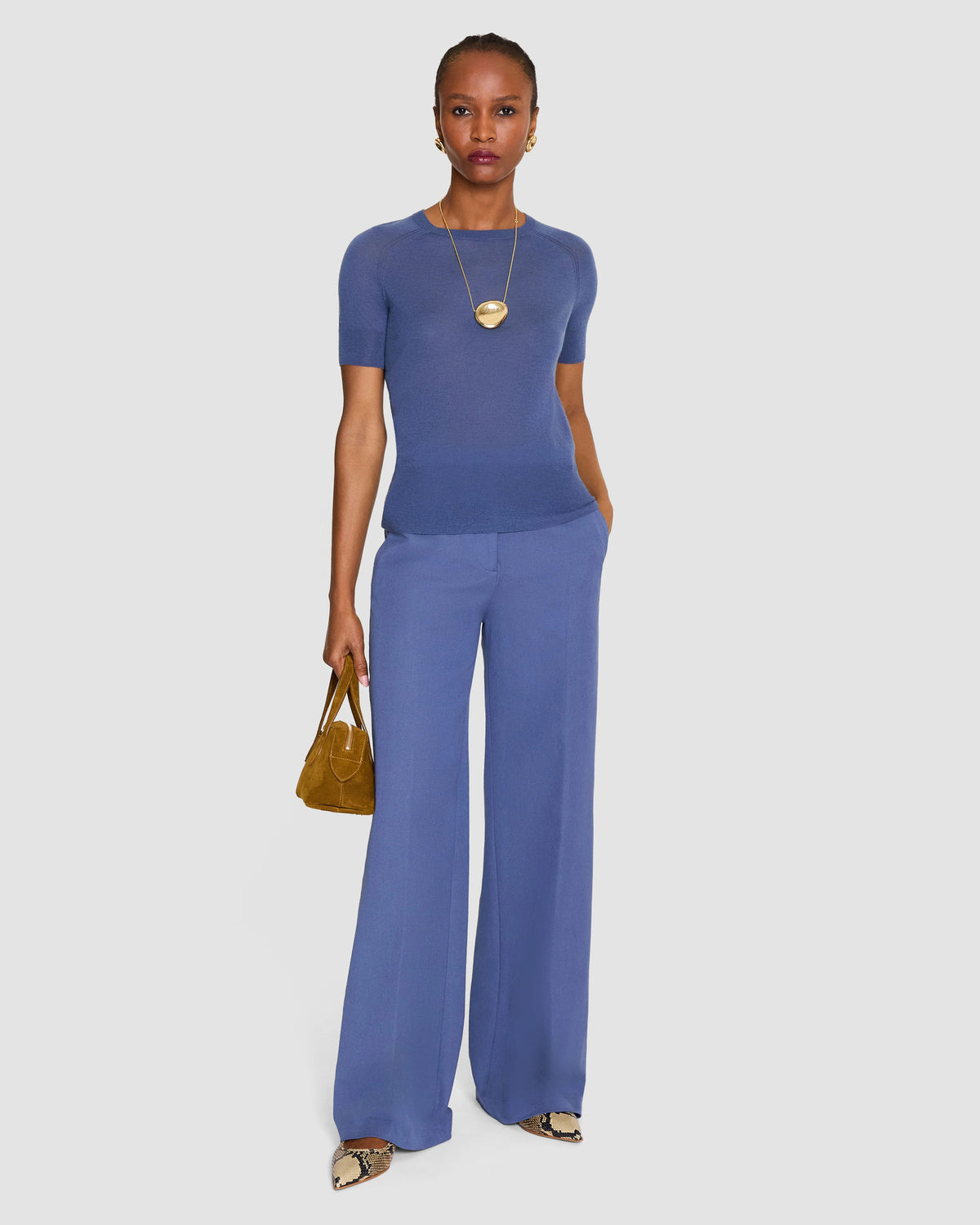 A model wearing a short-sleeve crewneck knit top in a dusty periwinkle blue from Christensen Copenhagen. 