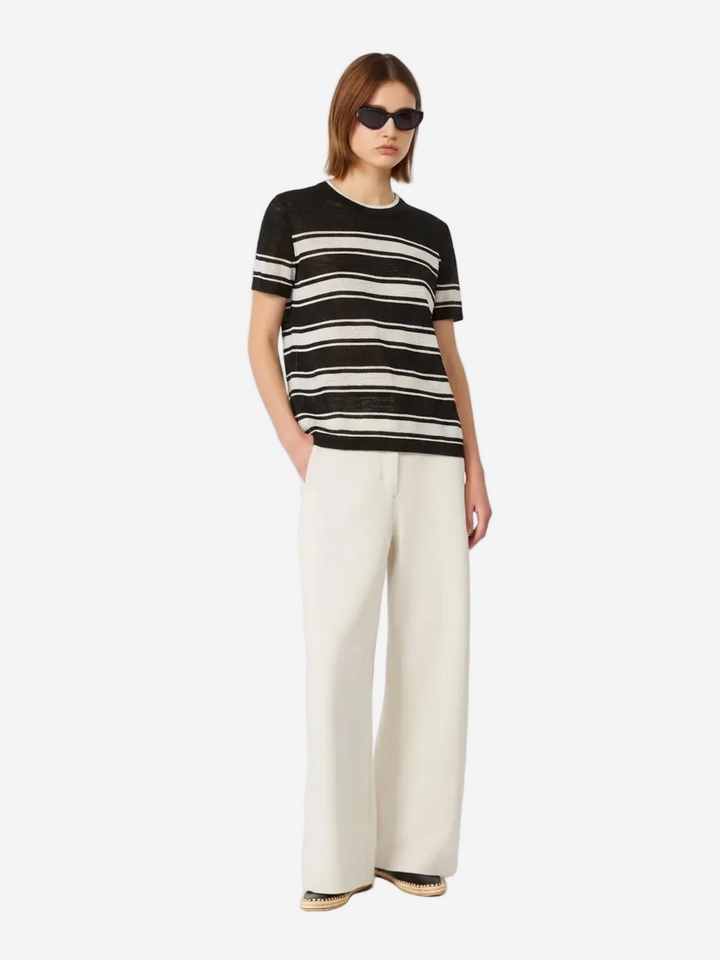 Person wearing a black and white striped shirt with wide-leg pants on a white background