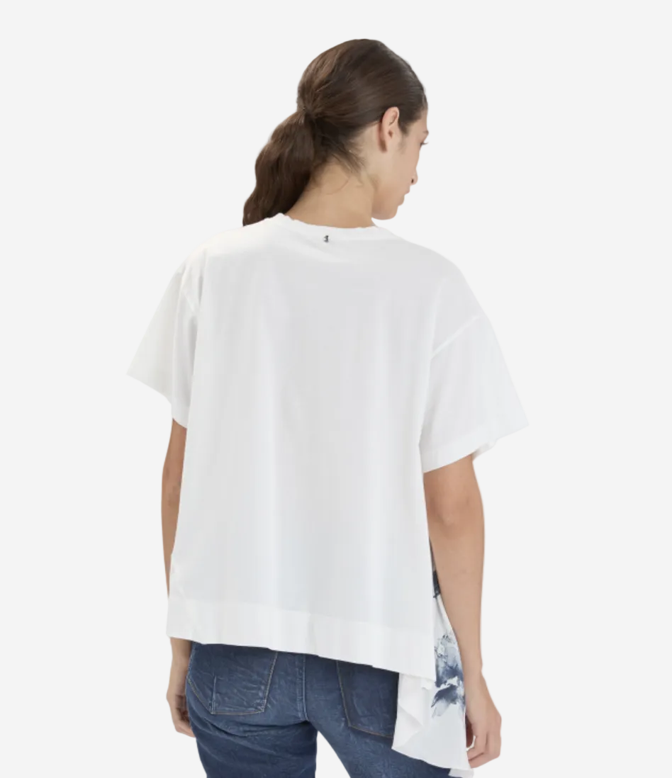 Woman wearing a white oversized shirt and blue jeans on a light gray background