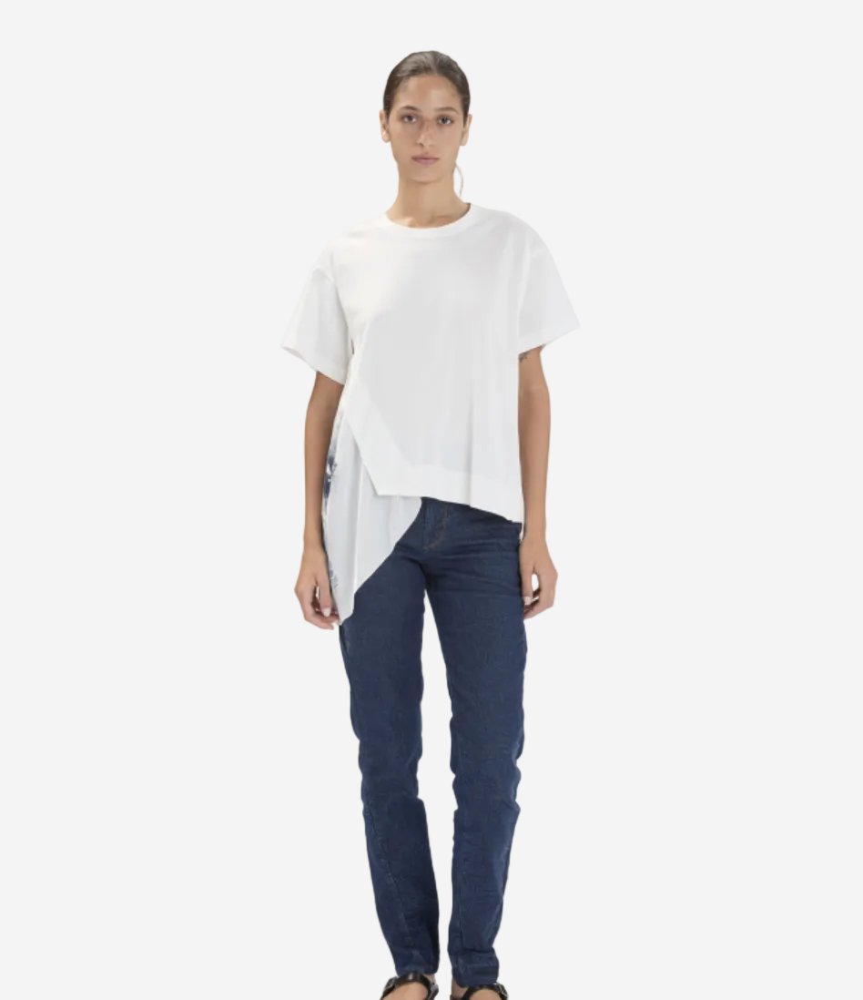Person wearing a white top and dark blue jeans on a plain background