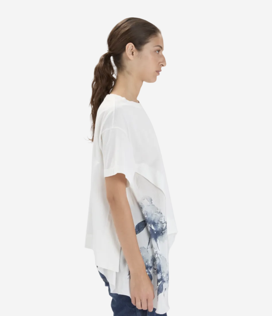 Woman wearing a white shirt with a floral design on a plain background