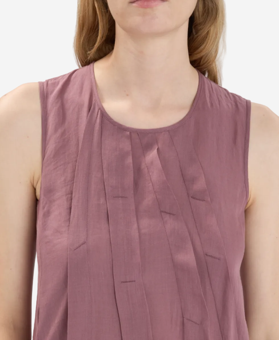 Person wearing a mauve sleeveless top against a plain background