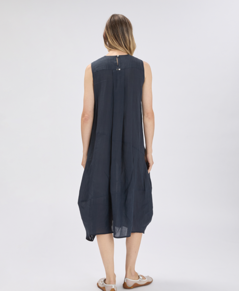 Woman wearing a sleeveless navy dress on a white background