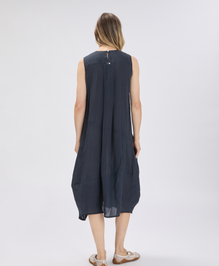 Woman wearing a sleeveless navy dress on a white background