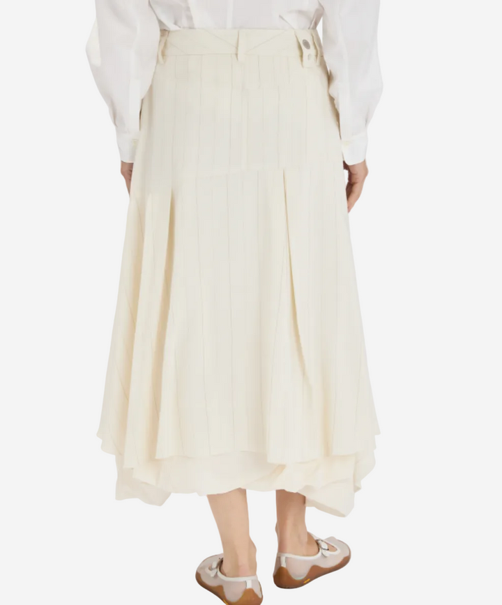 Person wearing a white shirt and cream-colored skirt on a white background