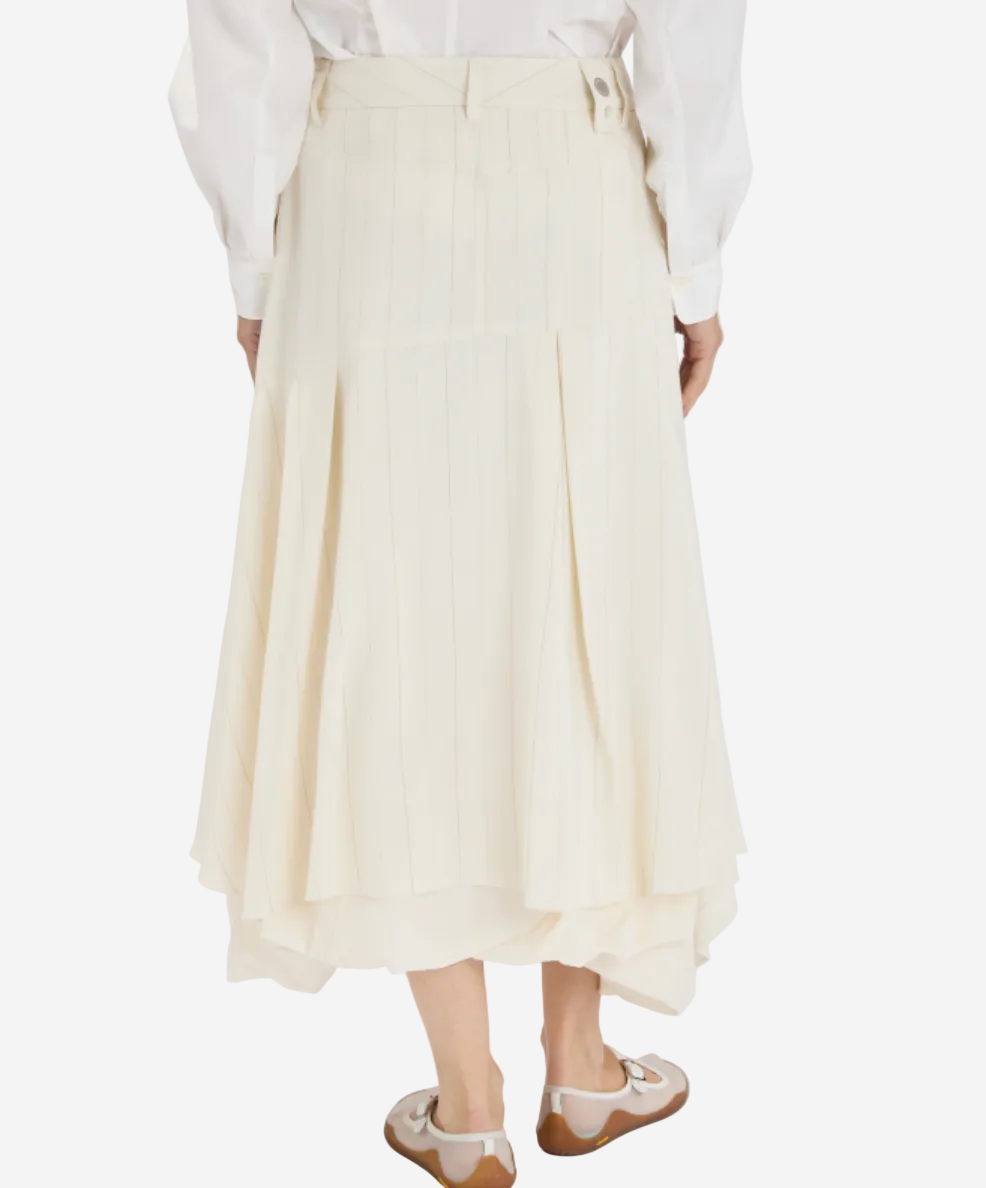Person wearing a white shirt and cream-colored skirt on a white background