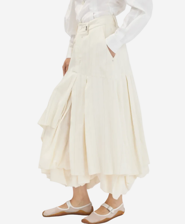 Person wearing a white blouse and cream-colored skirt on a white background