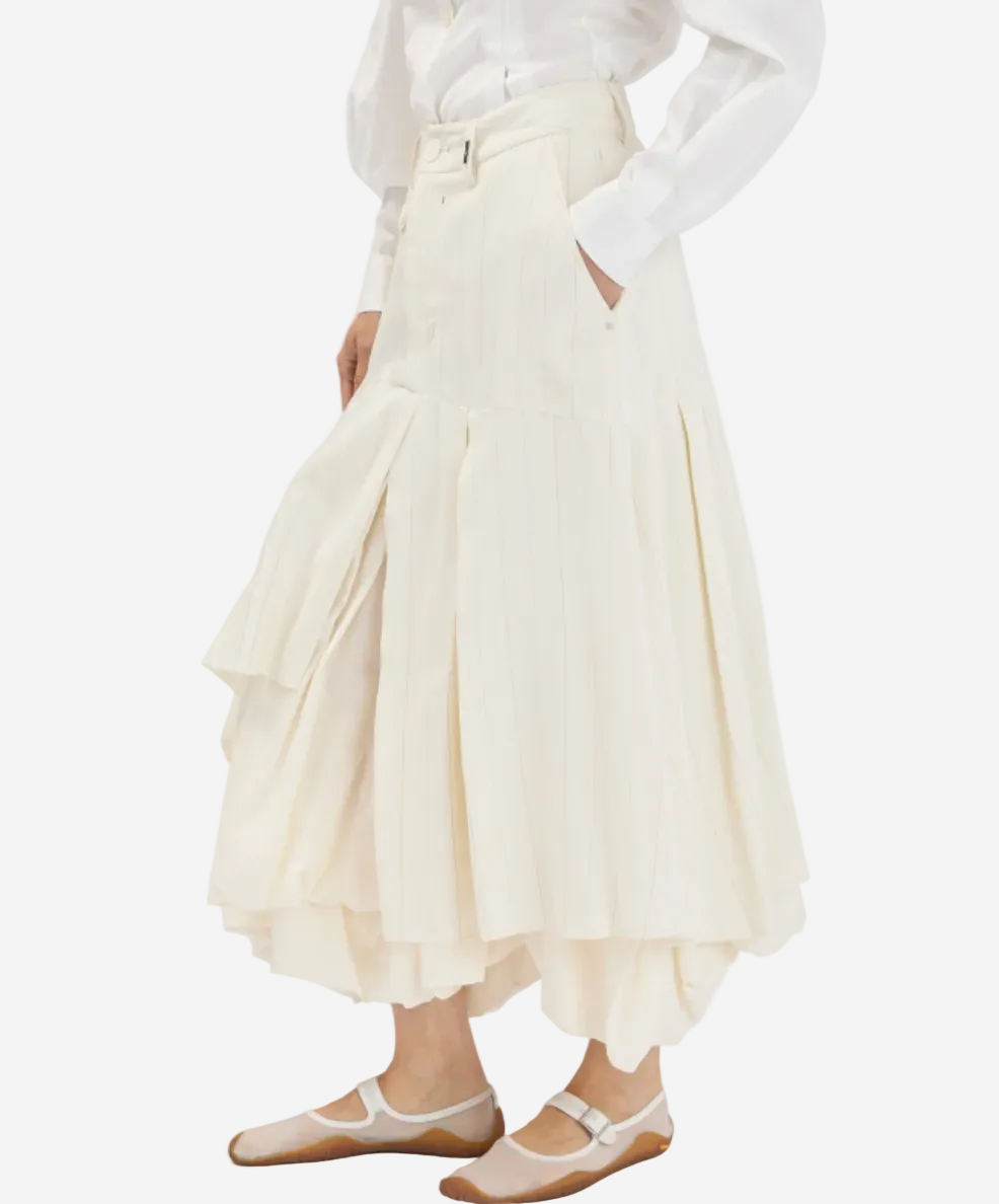 Person wearing a white blouse and cream-colored skirt on a white background