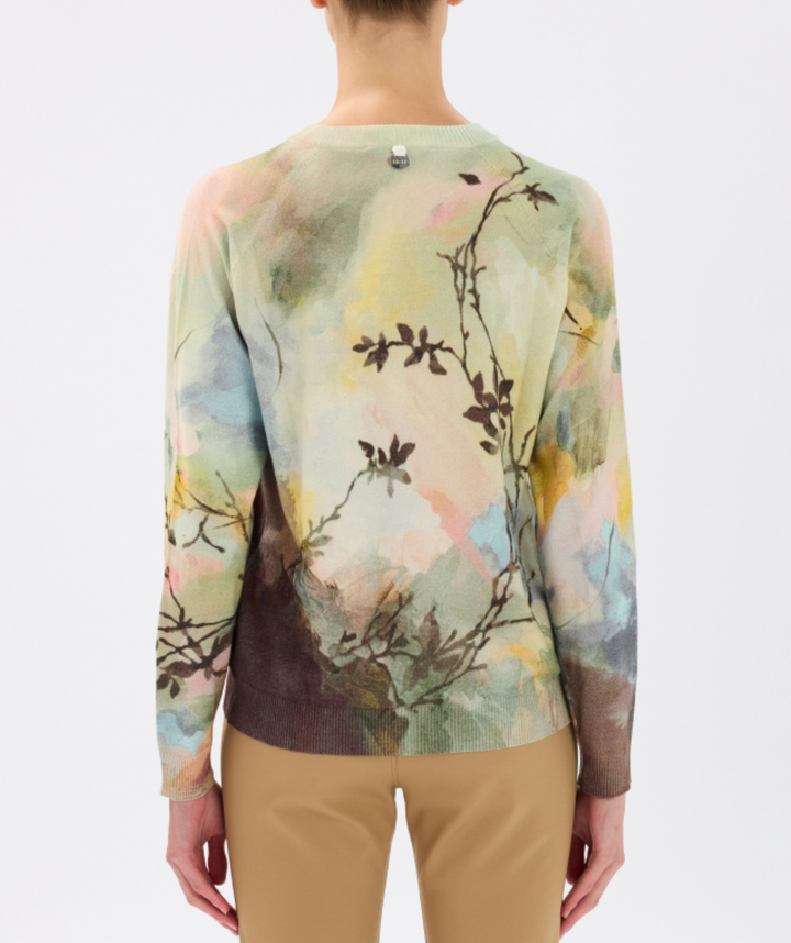 Person wearing a long-sleeve shirt with a nature-themed design on a plain background
